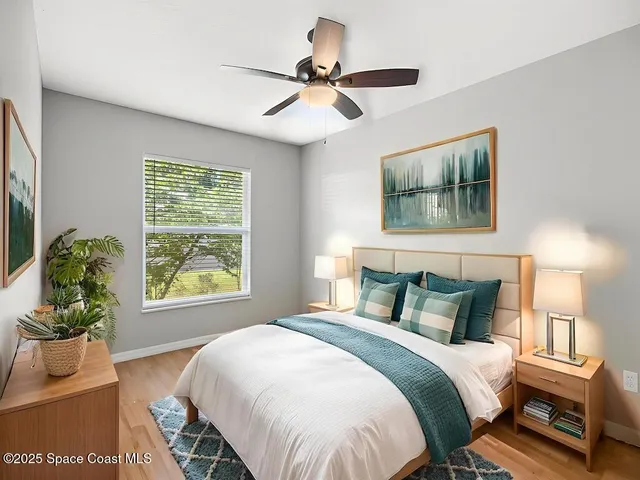 an empty room with wooden floor fan and windows
