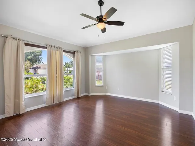 a view of an empty room with window and wooden floor