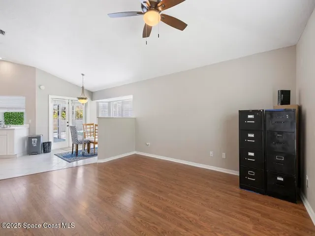 an empty room with wooden floor closet and windows