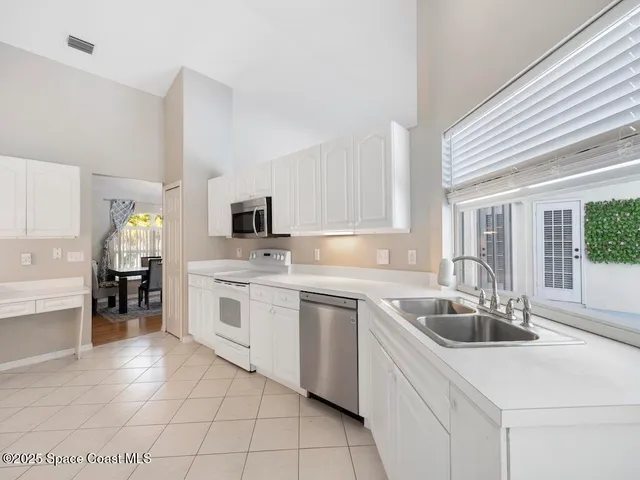 a kitchen with a refrigerator a sink dishwasher and a stove with white cabinets