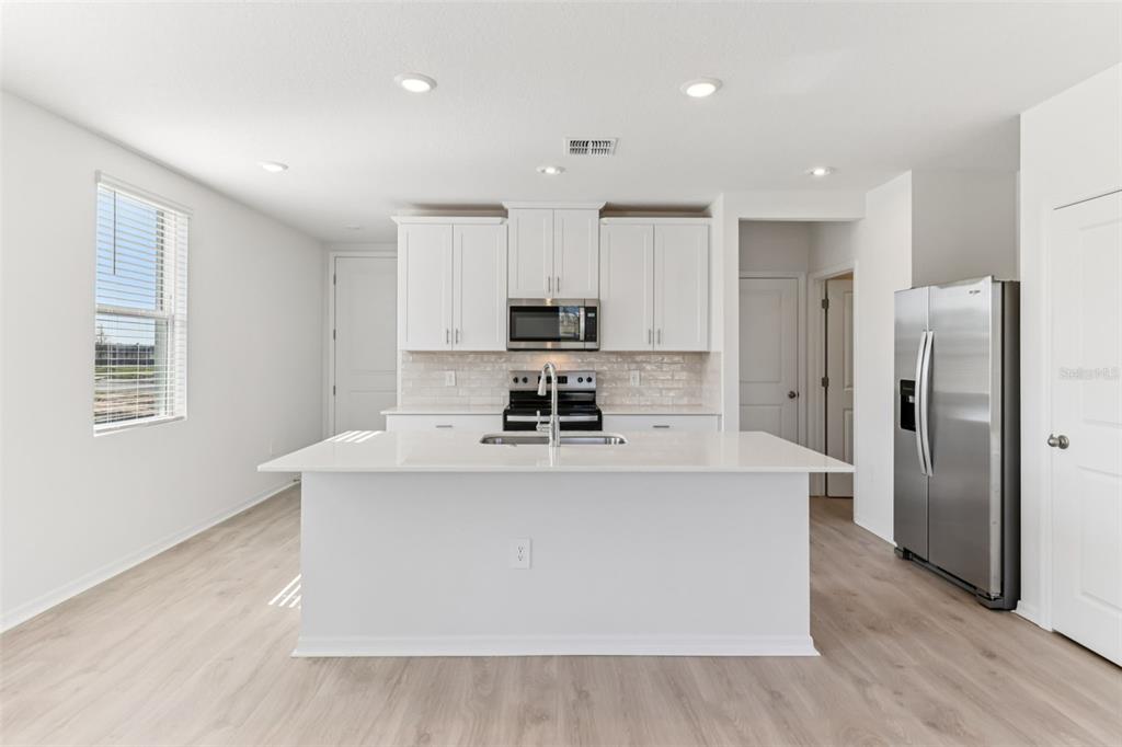 721 Spartina Street Lady Lake, FL 32159 - Photo 9 of 32 a view of kitchen with stainless steel appliances a refrigerator and a stove top oven