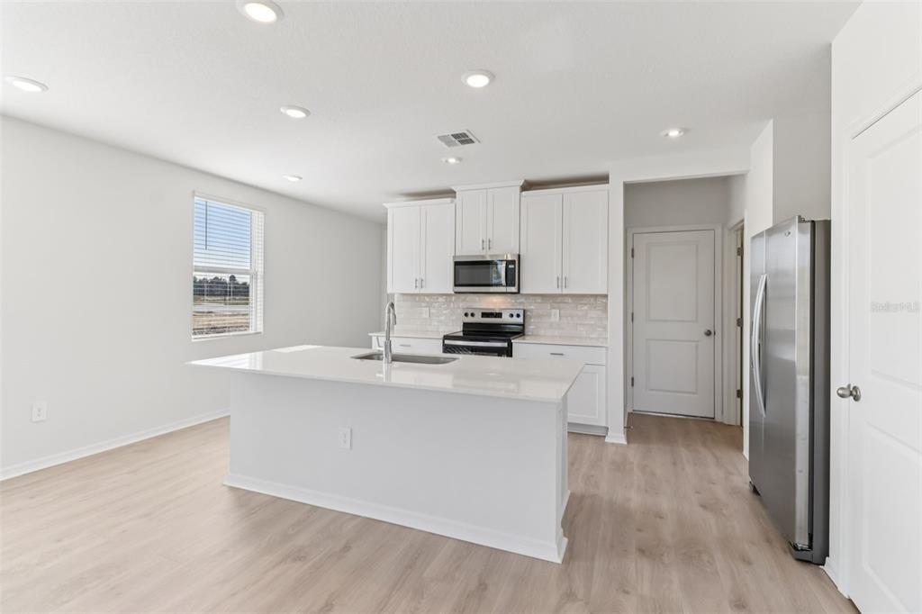 721 Spartina Street Lady Lake, FL 32159 - Photo 10 of 32 a kitchen with stainless steel appliances a sink stove and refrigerator