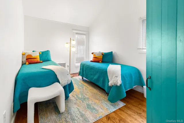 a bedroom with two beds and a chair with wooden floor