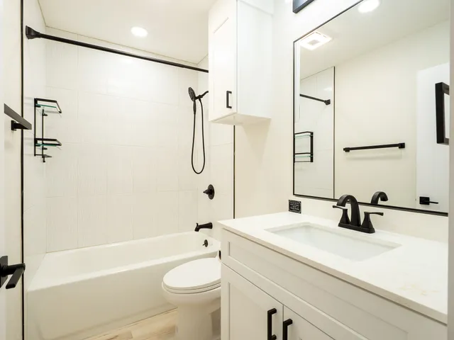 a bathroom with a sink a toilet a mirror and shower