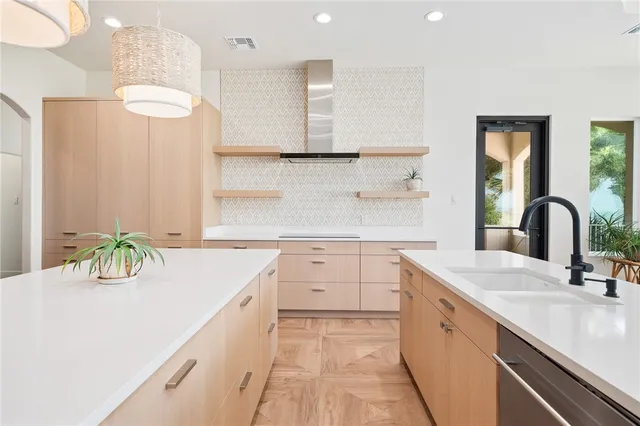 a large white kitchen with a sink a counter top space stainless steel appliances and cabinets