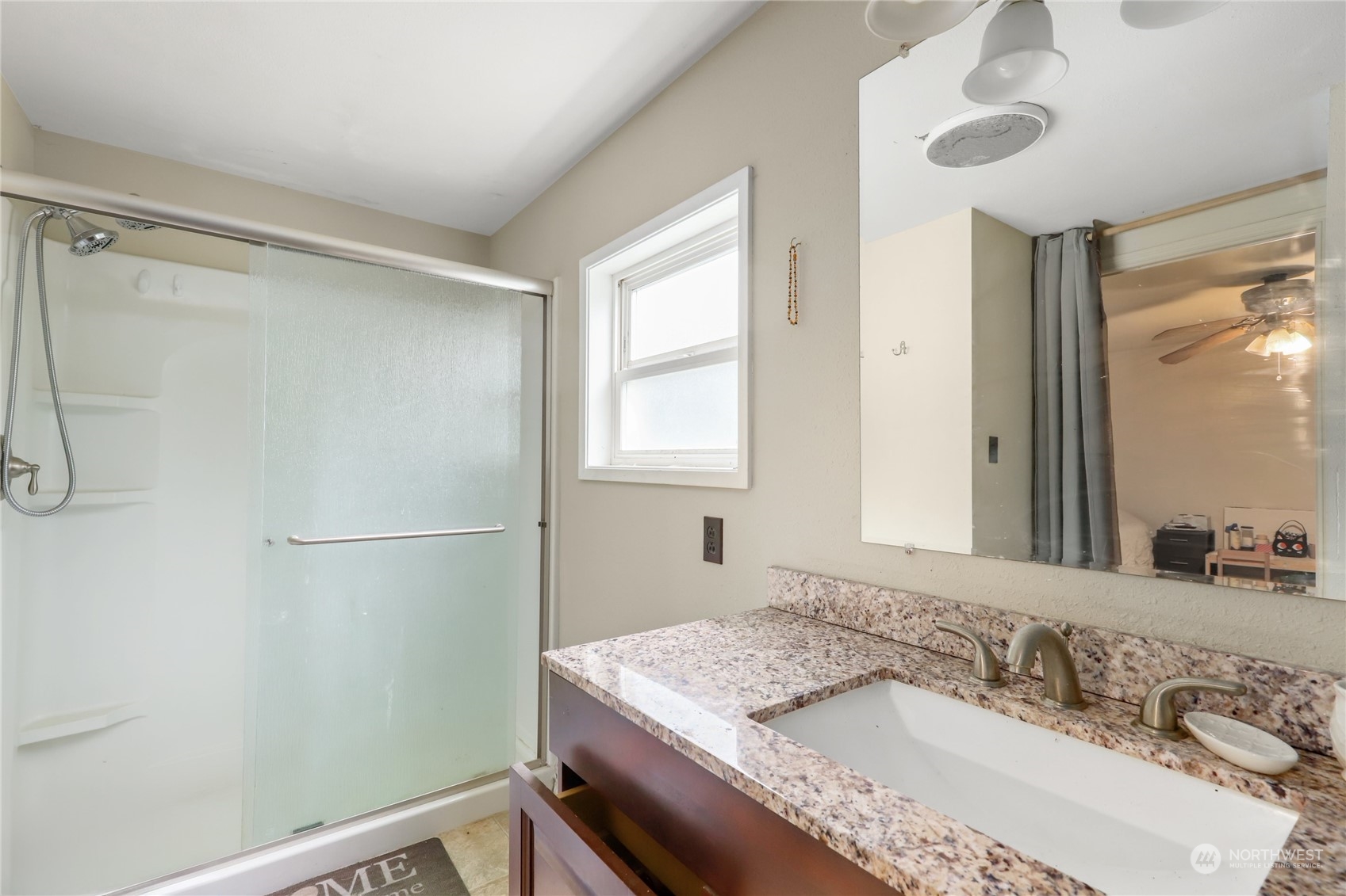 10909 Sidney Road Southwest Port Orchard, WA 98367 - Photo 17 of 34 a bathroom with a granite countertop sink a mirror and a shower