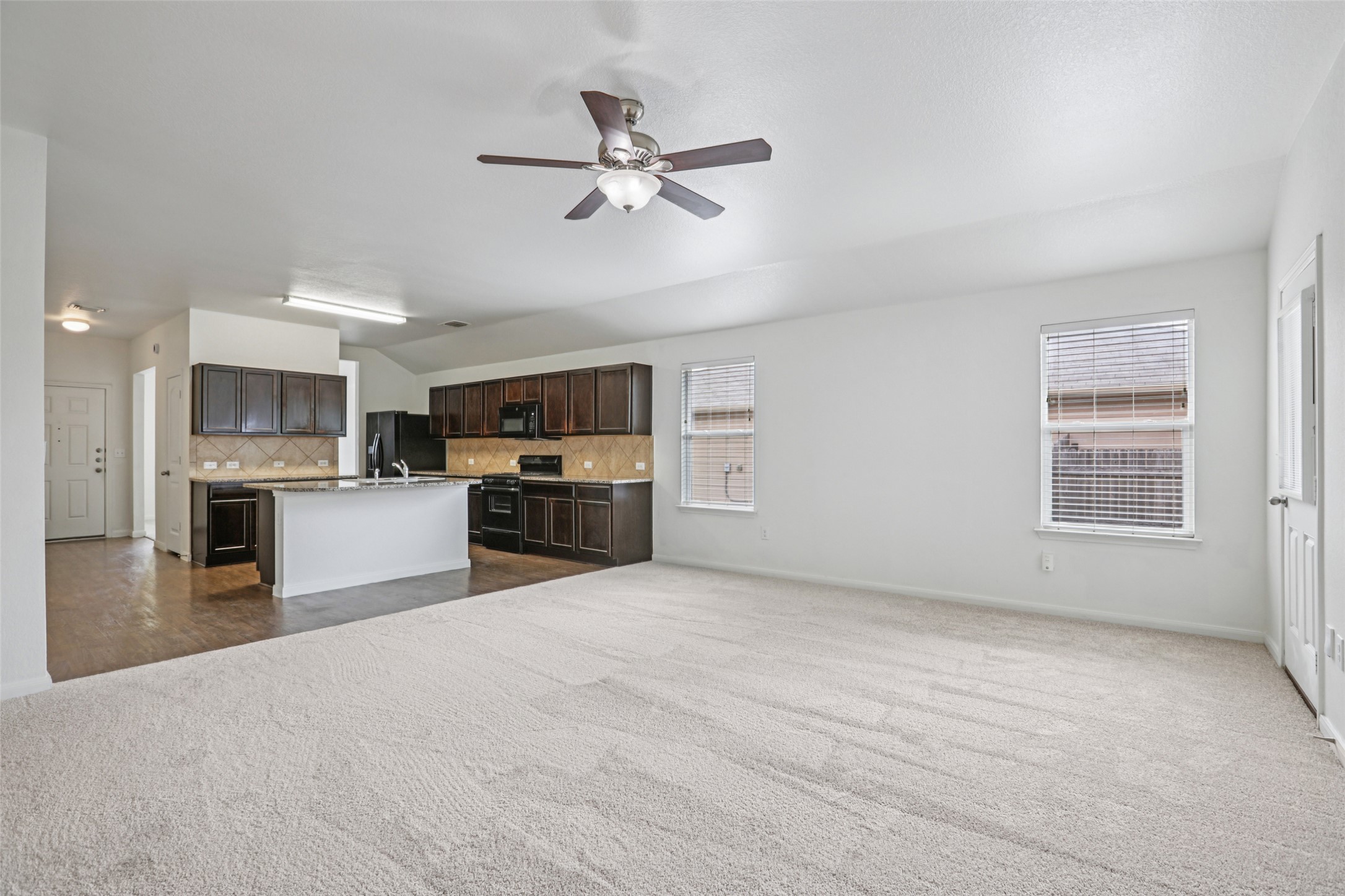 221 Alpha Kyle, TX 78640 - Photo 36 of 37 Kitchen with open floor plan, tasteful backsplash, dark wood finish cabinetry, black appliances, and lofted ceiling