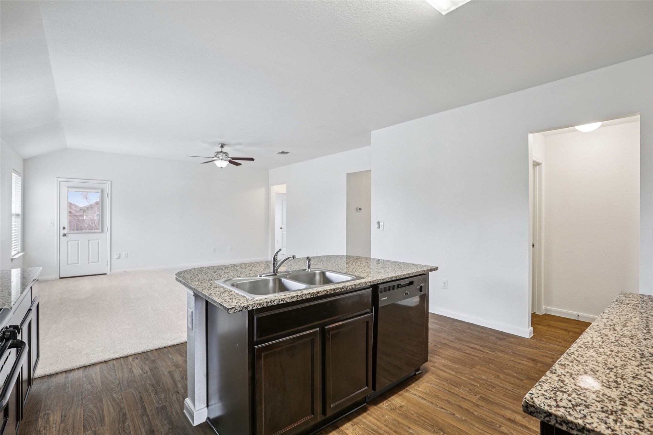 221 Alpha Kyle, TX 78640 - Photo 6 of 37 Kitchen featuring dark wood finish cabinets, a kitchen island with sink, ceiling fan, black dishwasher, and light stone countertops