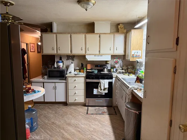 a kitchen with granite countertop a refrigerator stove top oven and sink
