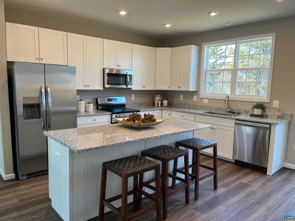 a kitchen with stainless steel appliances granite countertop a table chairs sink refrigerator and cabinets