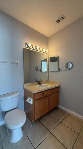 a spacious bathroom with a granite countertop toilet a sink and a mirror