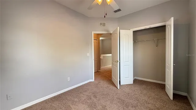 an empty room with closet and a chandelier fan