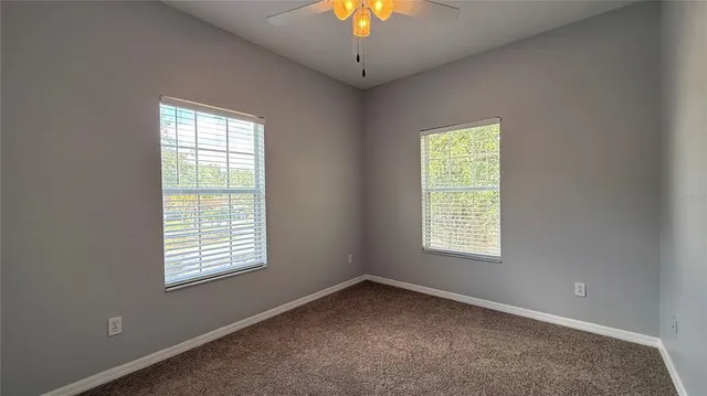 an empty room with a window and a chandelier fan