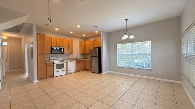 a kitchen with stainless steel appliances granite countertop a refrigerator a sink a stove top oven and a window