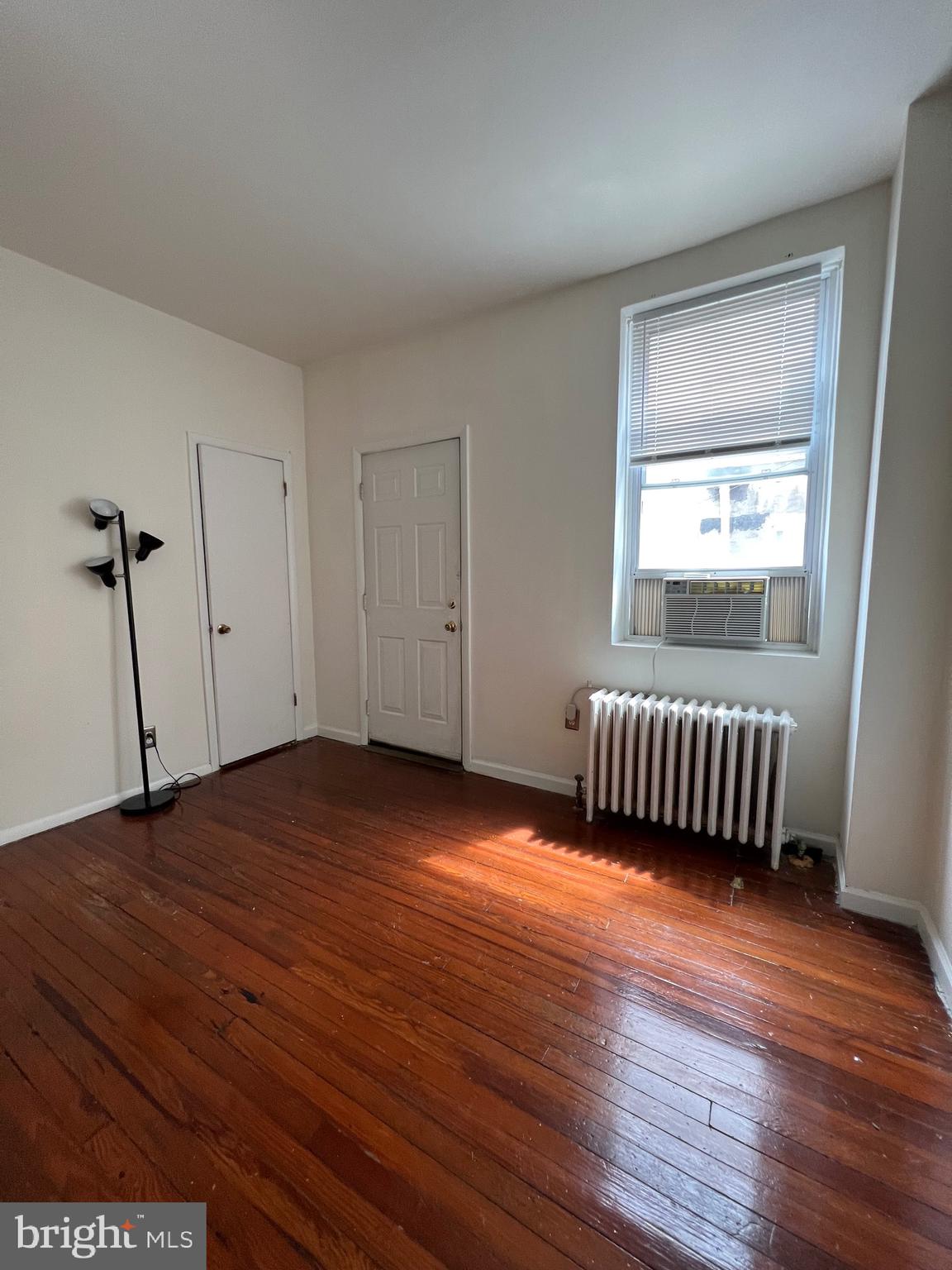 721 Bainbridge Street, Unit 2 Philadelphia, PA 19147 - Photo 3 of 8 a view of an empty room with wooden floor and a window