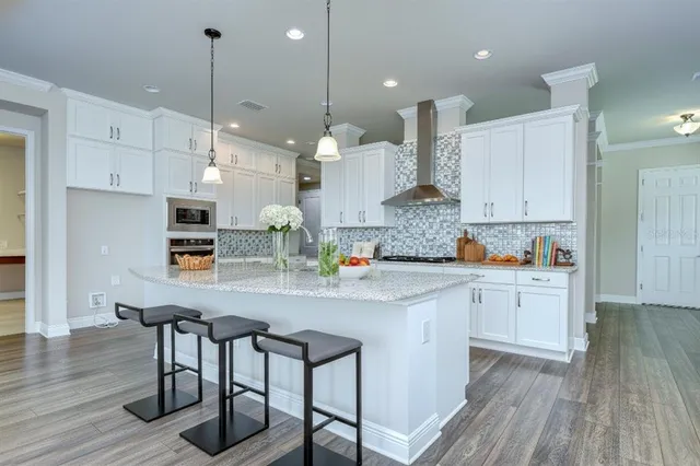 a kitchen with stainless steel appliances granite countertop a stove a sink dishwasher and a refrigerator with wooden floor