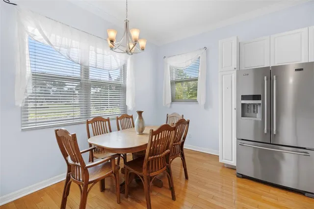 a kitchen with stainless steel appliances granite countertop a stove top oven a sink a dining table and chairs with wooden floor