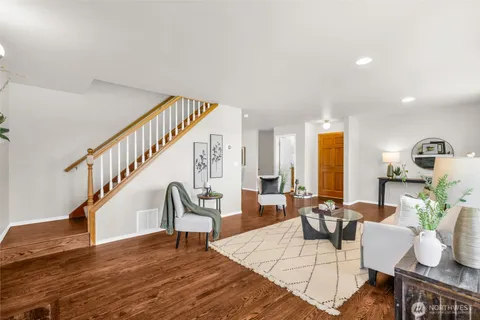 a living room with furniture and a dining table with wooden floor