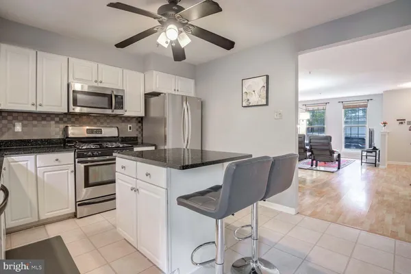 a kitchen with stainless steel appliances granite countertop a refrigerator a stove a microwave oven a sink with island and chairs