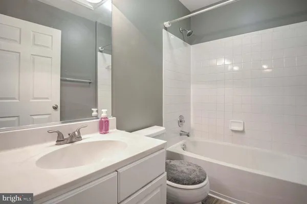 a bathroom with a granite countertop sink a toilet a mirror and bathtub