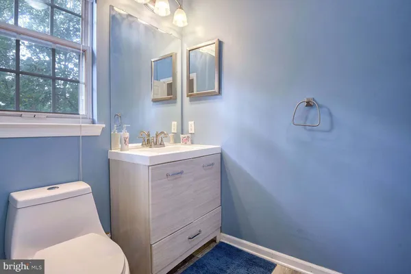 a bathroom with a toilet sink vanity and mirror