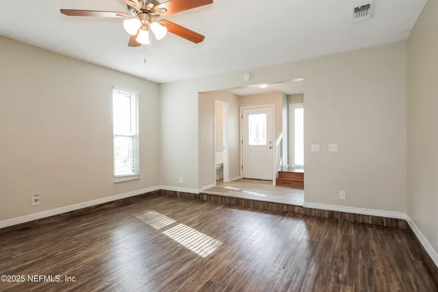 an empty room with wooden floor and windows