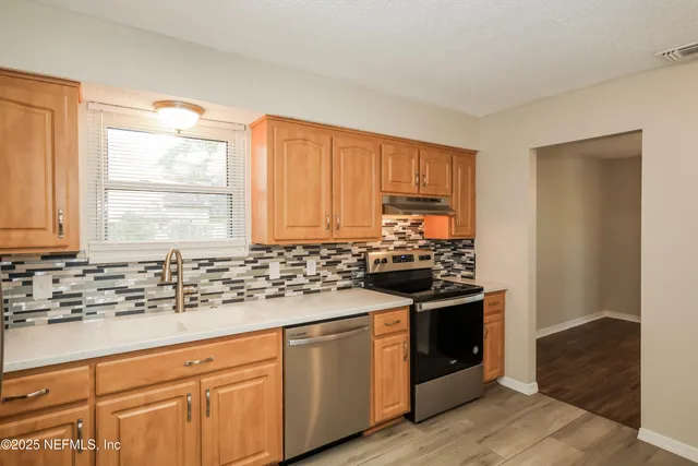 a kitchen with stainless steel appliances granite countertop a stove a sink and a microwave