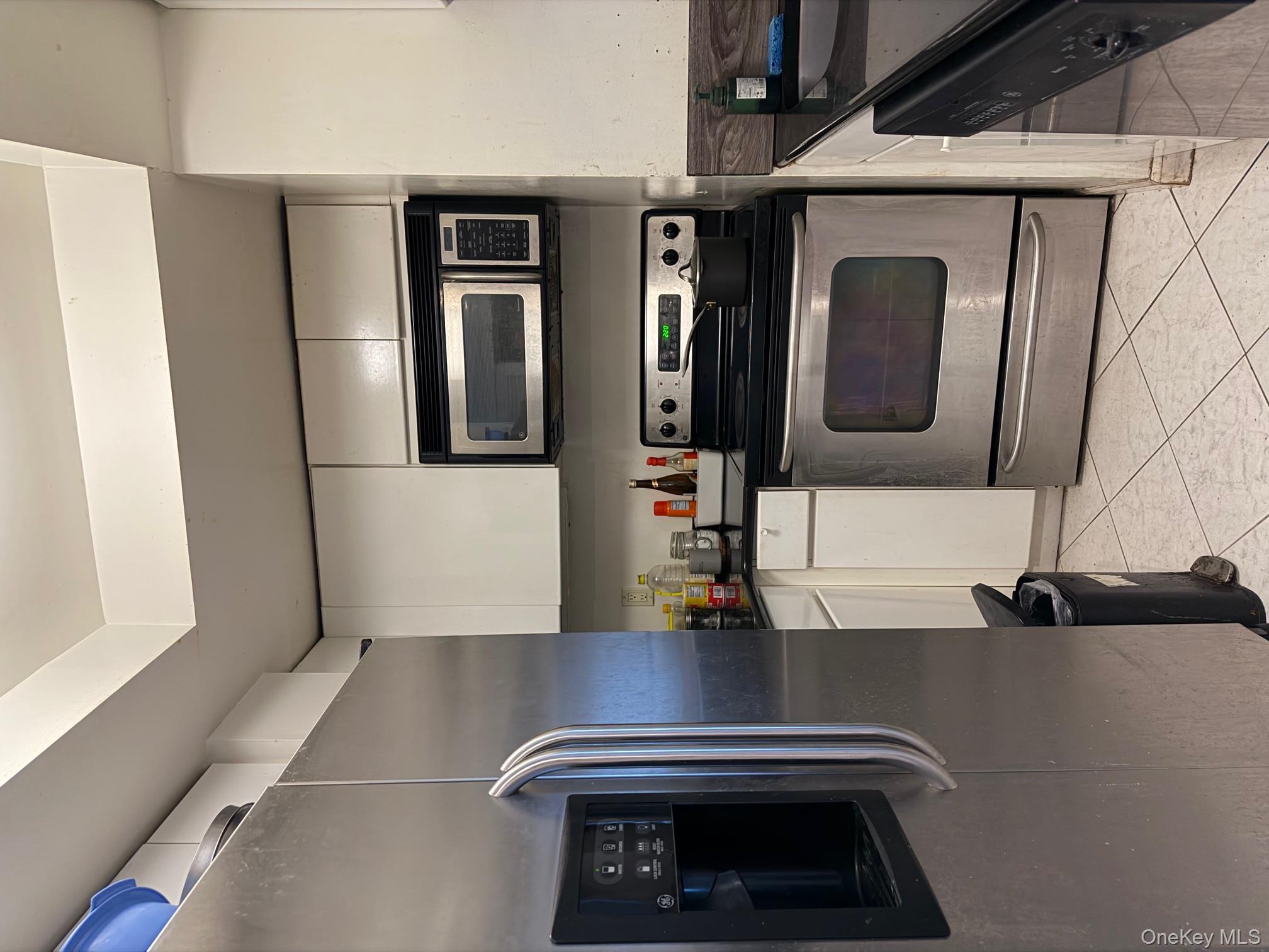 88 Cutter Mill Road, Unit 308 Great Neck, NY 11021 - Photo 5 of 15 Kitchen with stainless steel appliances, white cabinets, and light tile patterned floors