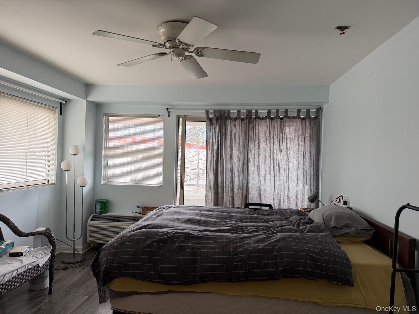 88 Cutter Mill Road, Unit 308 Great Neck, NY 11021 - Photo 8 of 15 Bedroom with wood finished floors, ceiling fan, and a wall unit AC