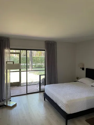 a bedroom with a balcony a bed and a large window