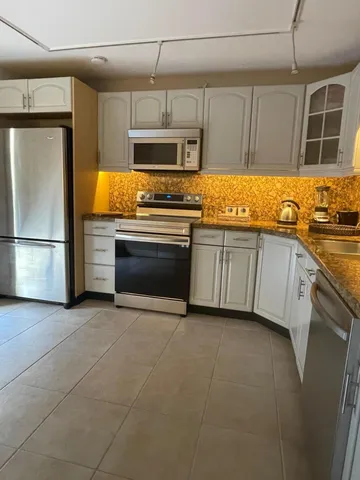 a kitchen with stainless steel appliances granite countertop a refrigerator a stove a sink and dishwasher