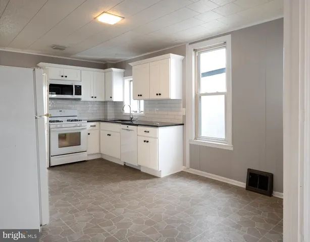 a kitchen with granite countertop a sink cabinets stainless steel appliances and a window