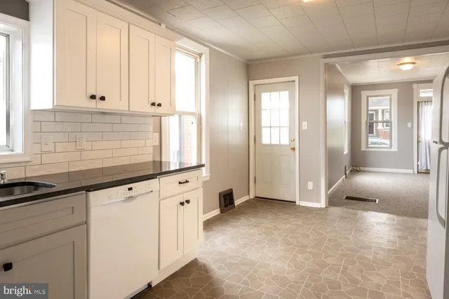 a view of kitchen with granite countertop white cabinets and sink