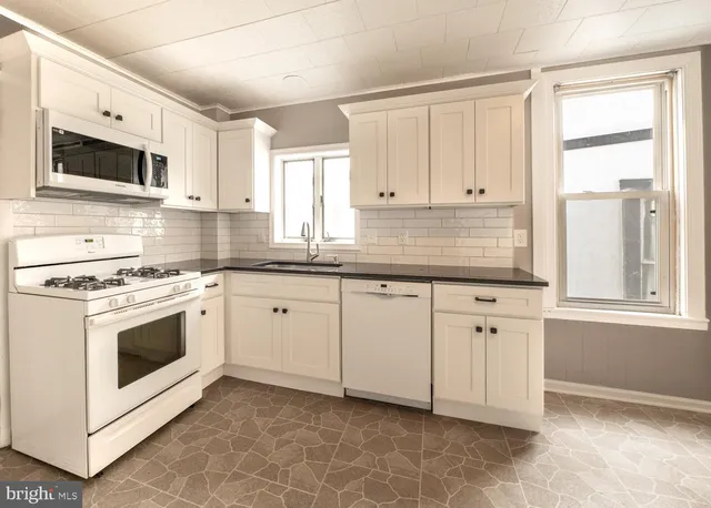 a kitchen with granite countertop white cabinets and white appliances