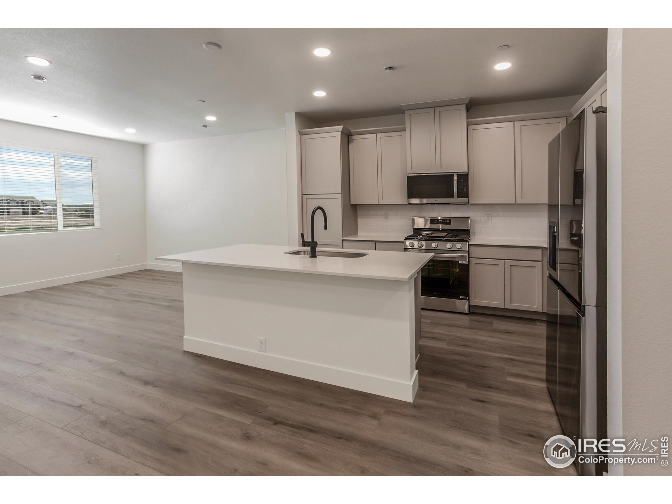 4909 Autumn Leaf Drive Timnath, CO 80547 - Photo 12 of 34 a kitchen with stainless steel appliances granite countertop a sink a stove a refrigerator with wooden floors