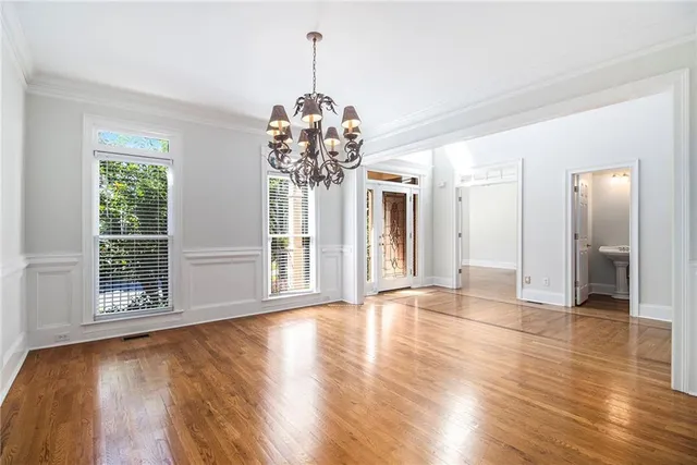 a view of a livingroom with wooden floor a ceiling fan and windows