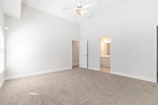 an empty room with windows and ceiling fan