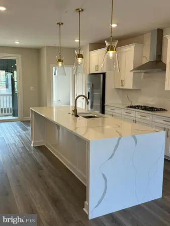 a kitchen with stainless steel appliances granite countertop a sink a stove a refrigerator and island with wooden floor