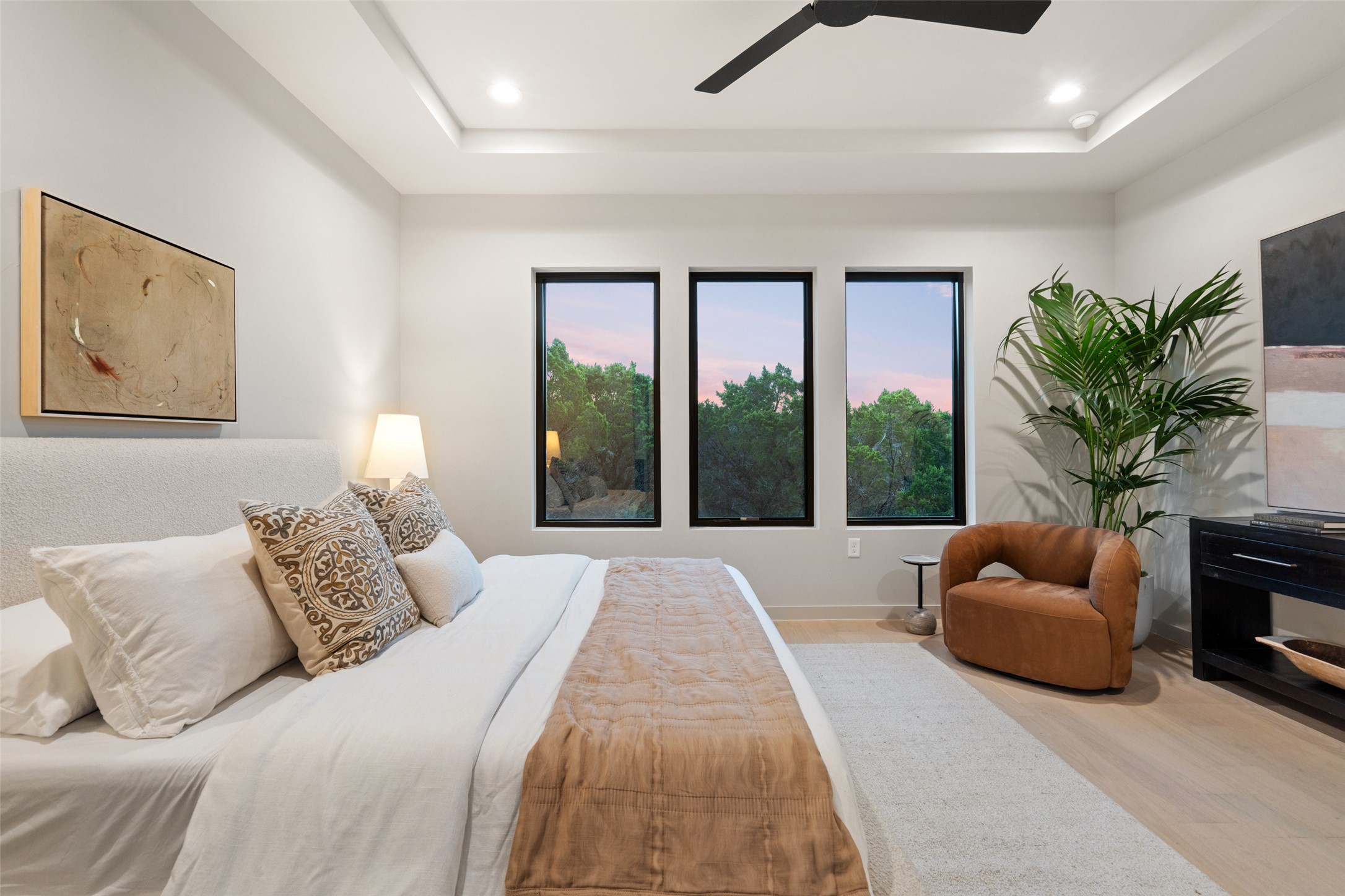 9803 Ribelin Ranch Court, Unit 19 Austin, TX 78750 - Photo 7 of 14 Natural light streams into this serene bedroom, highlighting the sleek tray ceiling and wooded views.