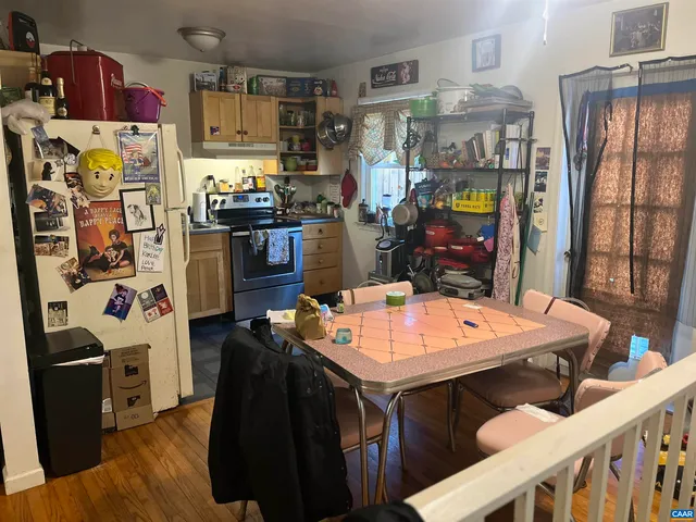 a room with stainless steel appliances kitchen island granite countertop a table chairs and a refrigerator