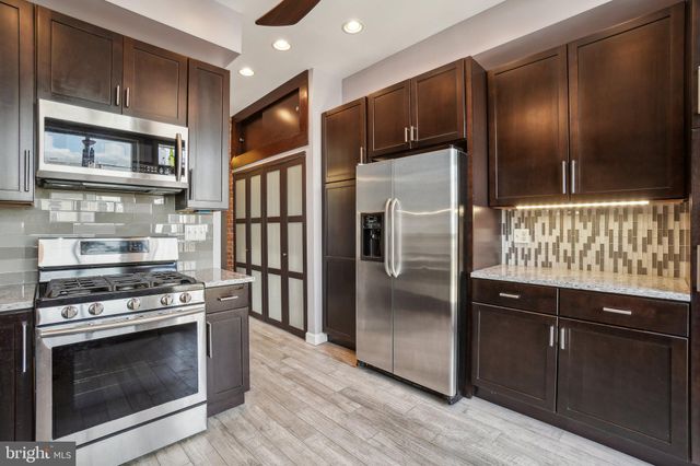 a kitchen with stainless steel appliances granite countertop a refrigerator a stove and a sink with wooden floor