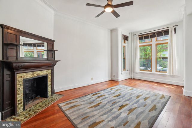a view of an empty room with wooden floor fireplace and a window