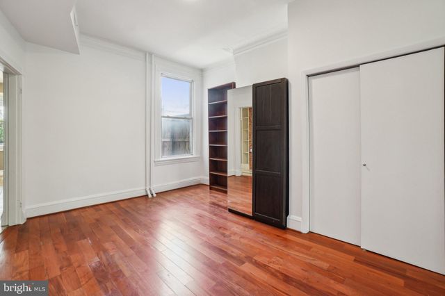 a view of an empty room with wooden floor and closet