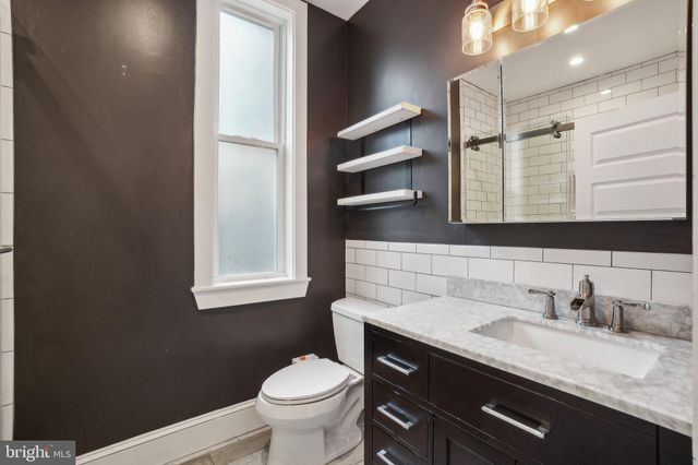 a bathroom with a granite countertop sink toilet and mirror