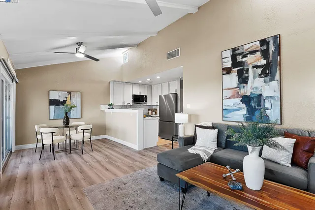 a living room with furniture wooden floor and kitchen view