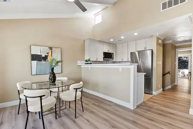 a kitchen with stainless steel appliances a refrigerator a stove a microwave oven with a dining table and chairs