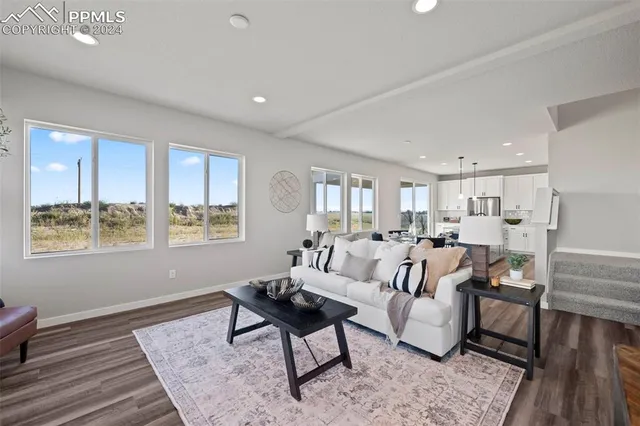 a open kitchen with stainless steel appliances granite countertop a stove a sink a dining table and chairs with wooden floor