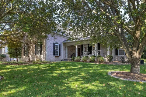 a front view of a house with a garden and trees