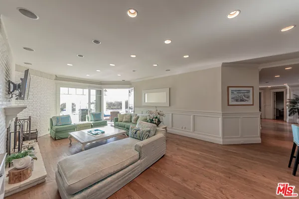 a living room with furniture and a kitchen view with wooden floor