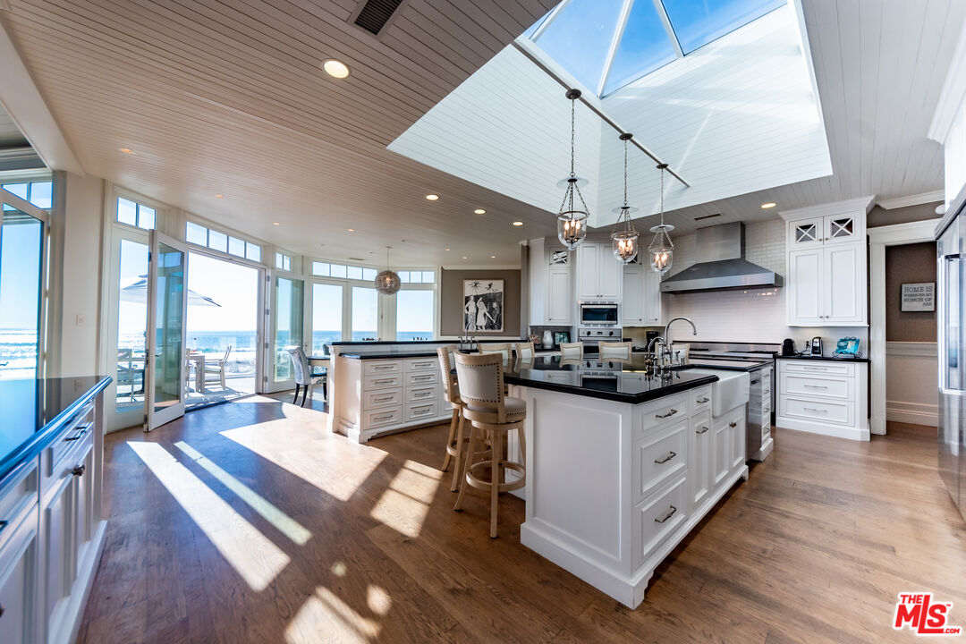 30760 Broad Beach Road Malibu, CA 90265 - Photo 6 of 41 a kitchen with stainless steel appliances a stove a sink dishwasher and a dining table with wooden floor